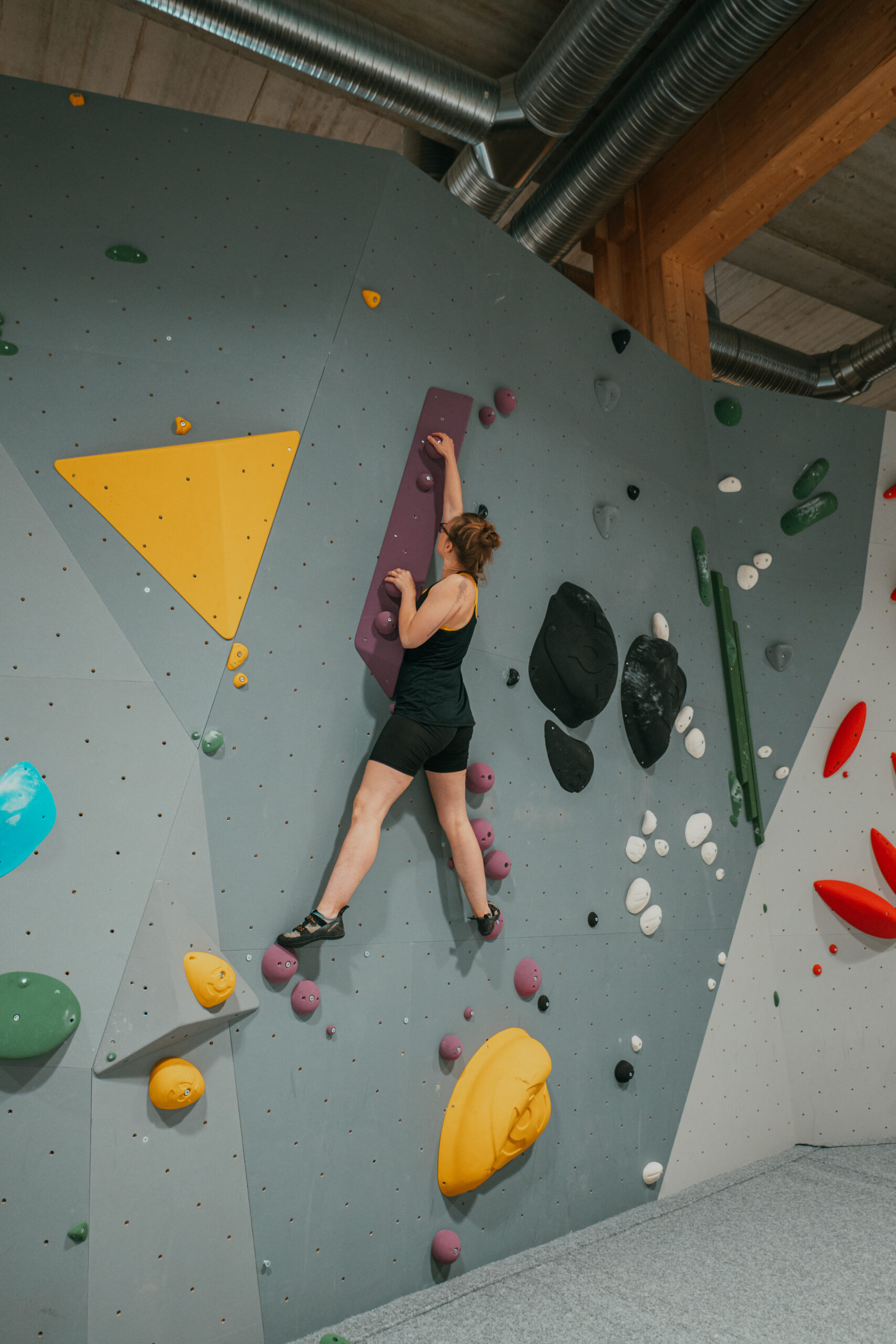 kvinnlig klättrare på bouldervägg